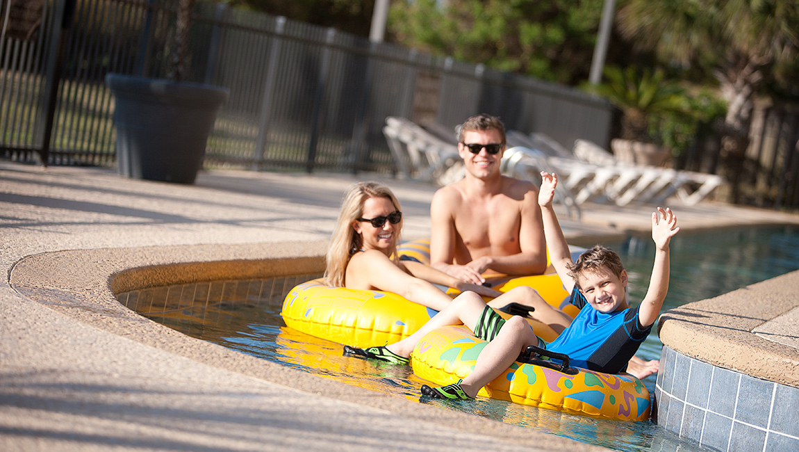 A family of three enjoys a leisurely float down a pool.